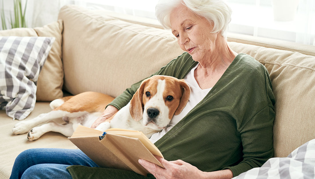 Femme lisant avec un chien sur les genoux