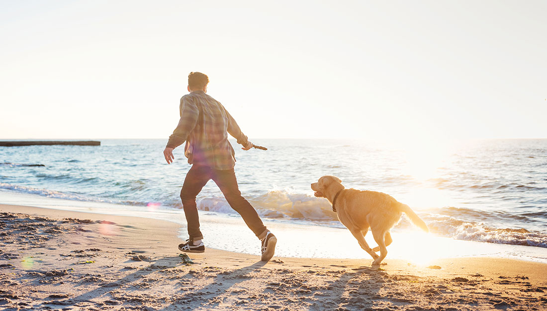 homme qui court sur la plage avec un chien