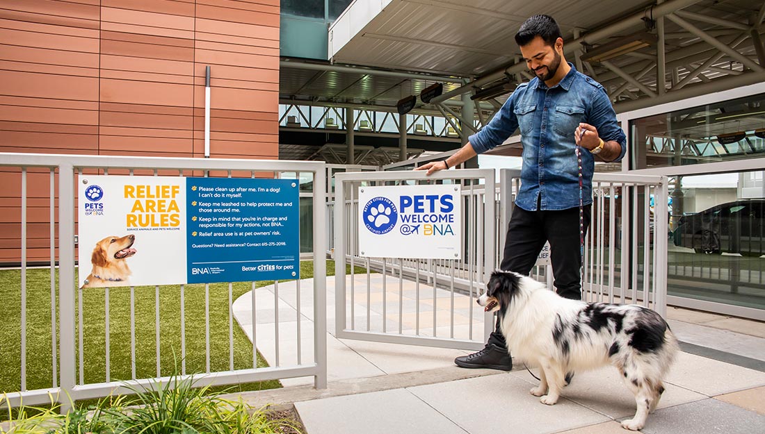 man with dog entering airport pet relief area