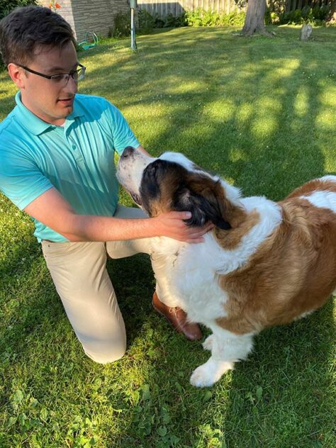 Le maire Sorenson à genoux avec un Saint-Bernard sur l'herbe