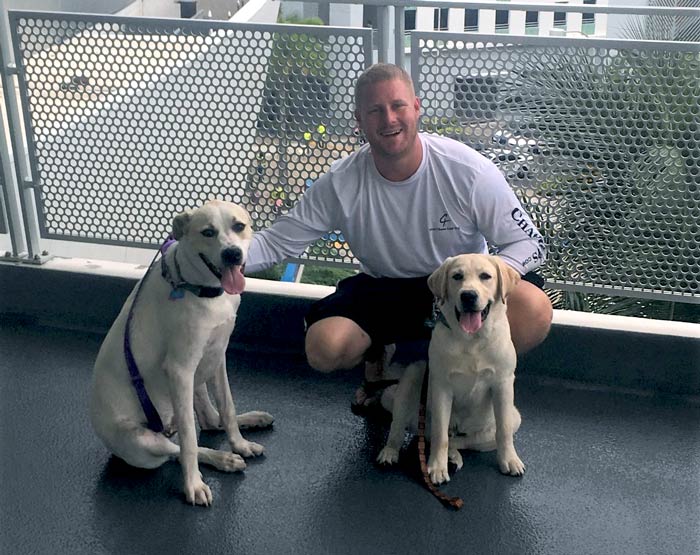 Le maire AJ Ryan s'accroupit pour poser avec ses deux adorables chiens, Jackson et Banjo.