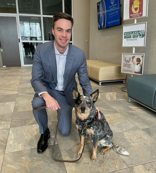 Mayor Coleman kneels next to adorable dog Daisy.
