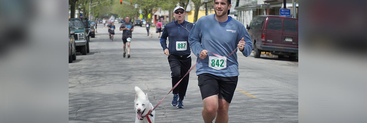 foot race with dogs||a man and dog running in a dog-friendly 5K in Fort Wayne