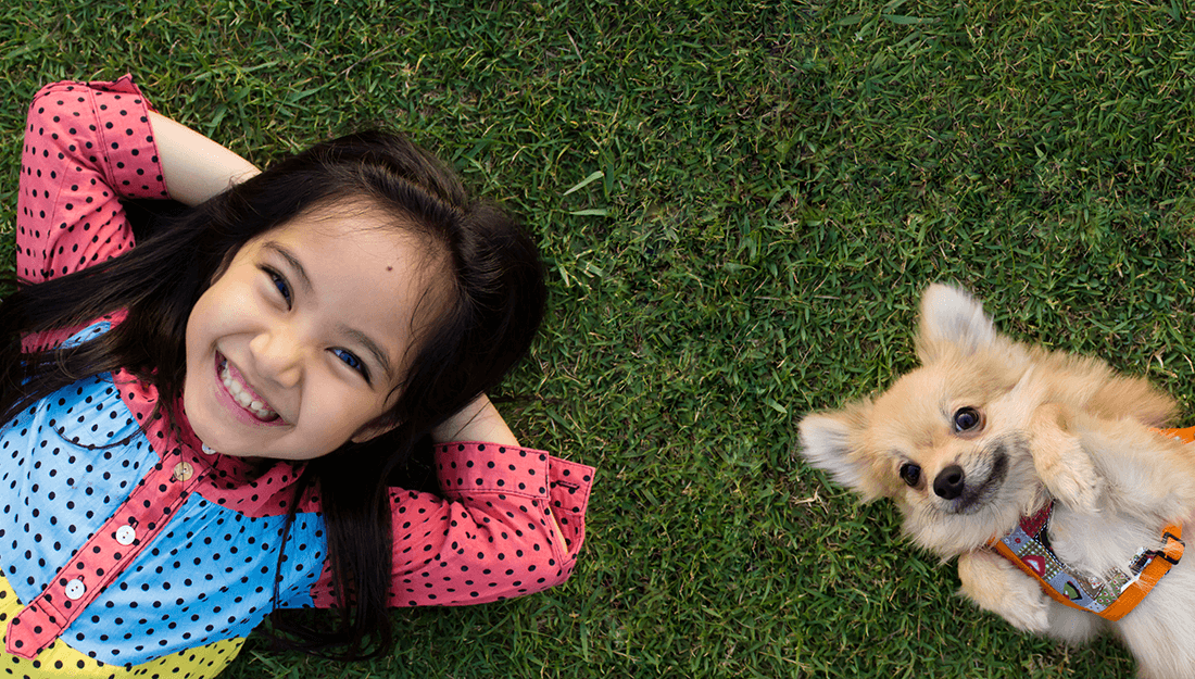 girl and dog outside lying on grass