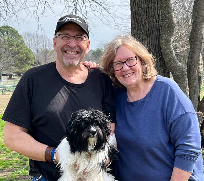 Un homme et une femme tenant un mignon chien pelucheux blanc et noir au parc.